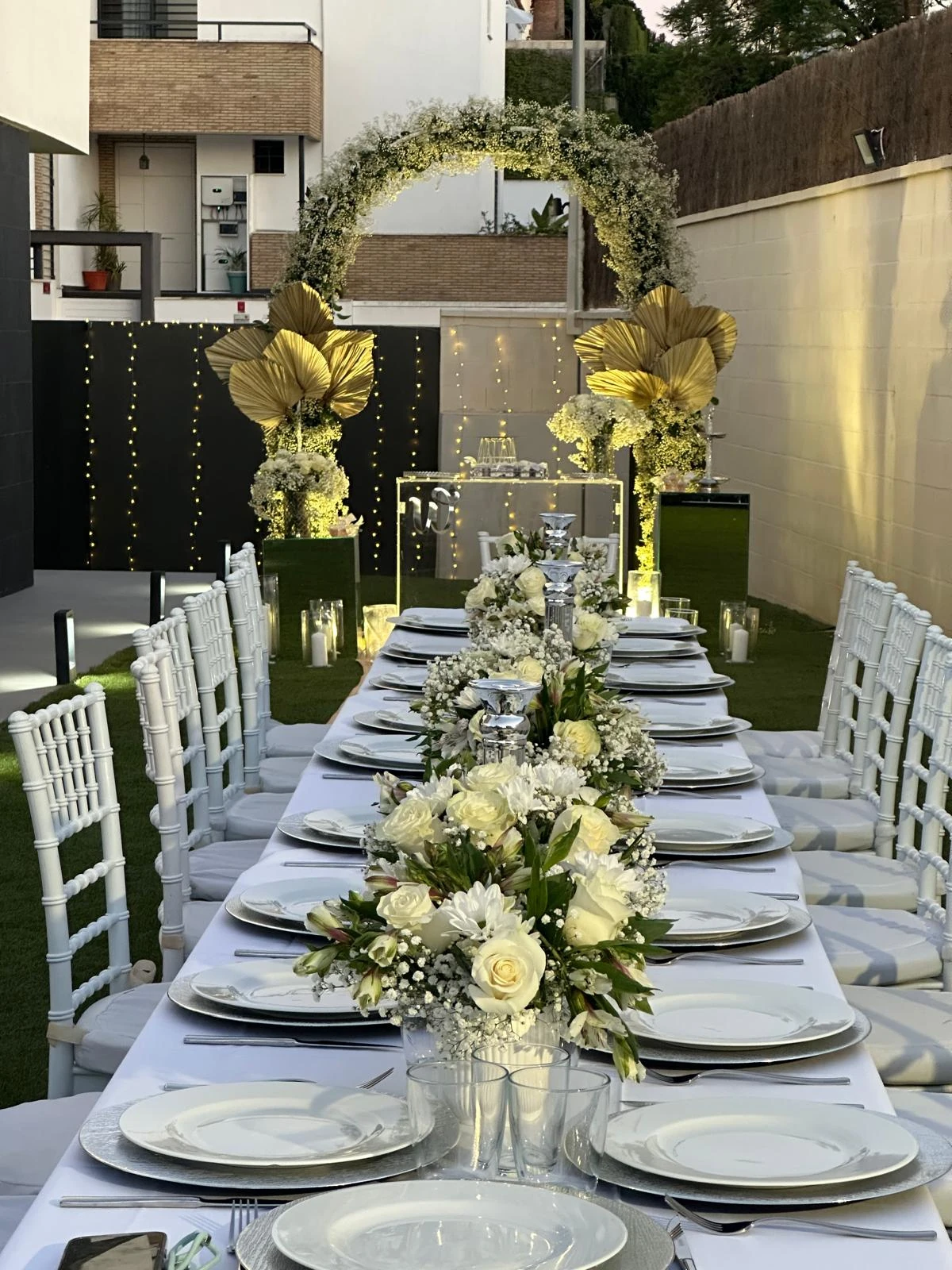 Mesa de banquete de boda al aire libre con arco floral de flor de bebé y detalles dorados