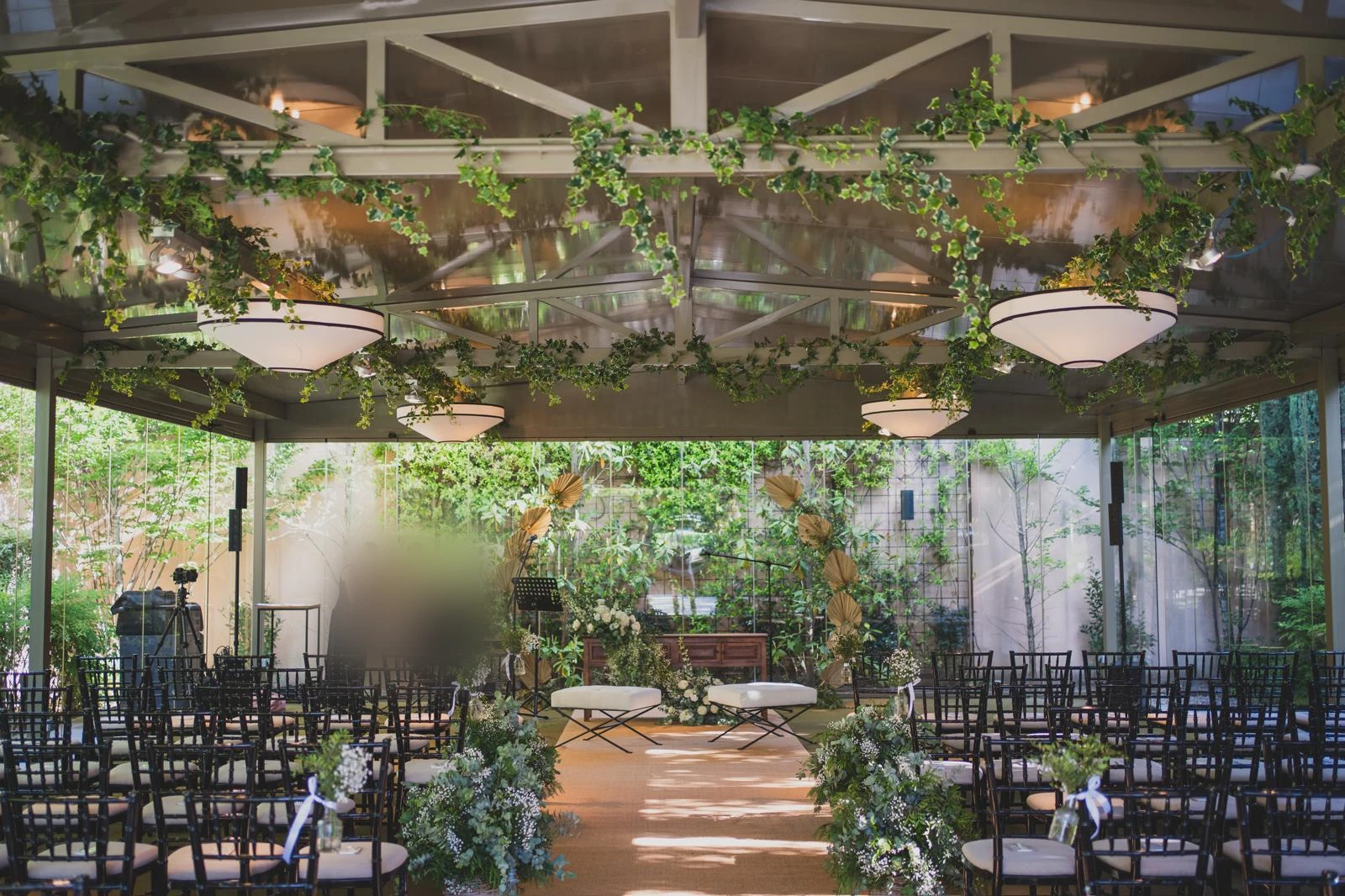 Ceremonia de boda al aire libre bajo pérgola con enredaderas, sillas Chiavari y pasillo decorado con eucalipto